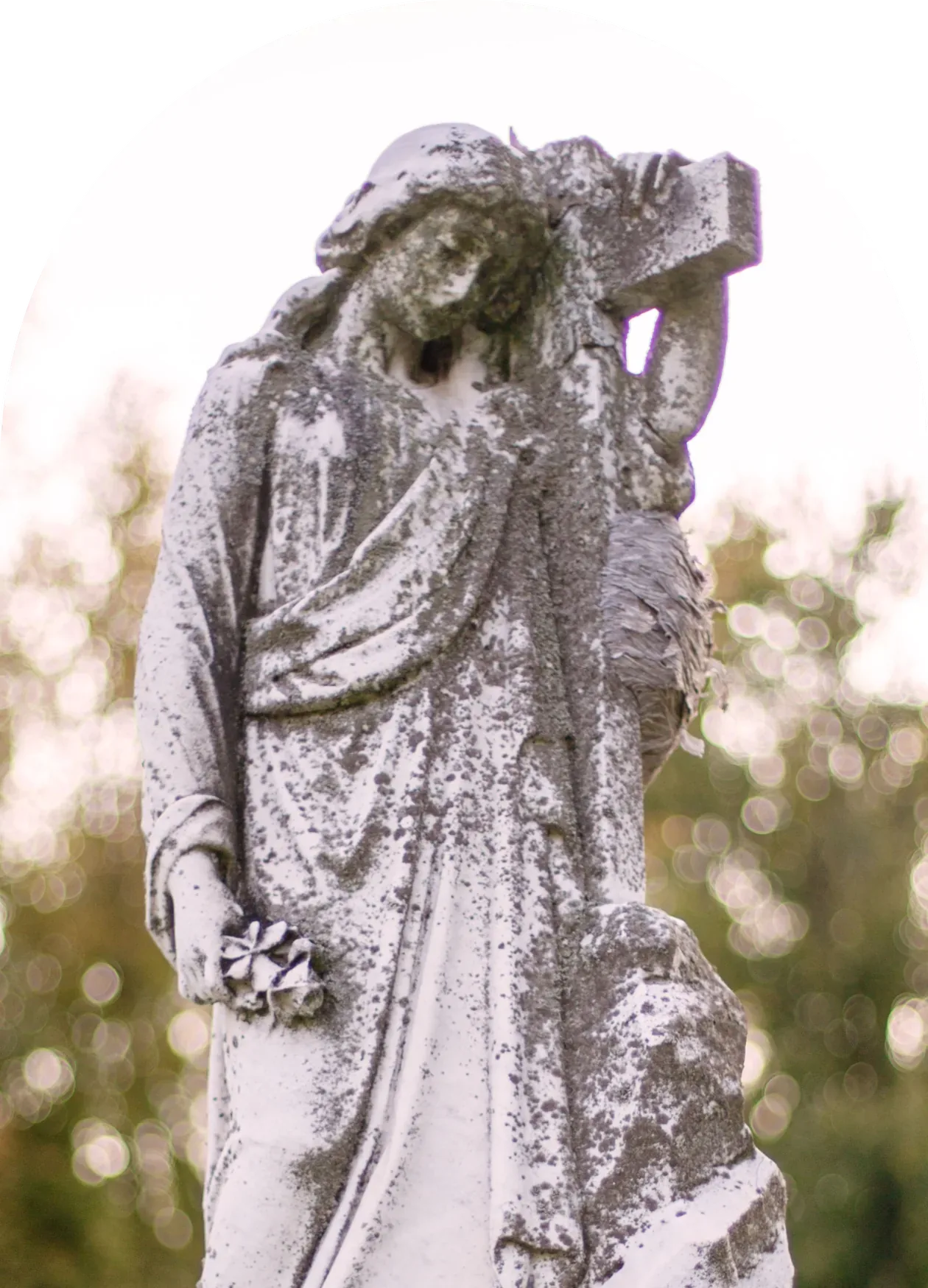 Weathered marble statue of a mourning woman holding a cross atop a granite monument